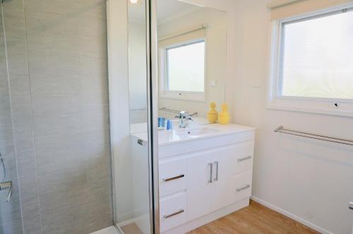 a white bathroom with a sink and a shower at Bayview Hideaway in Point Lonsdale