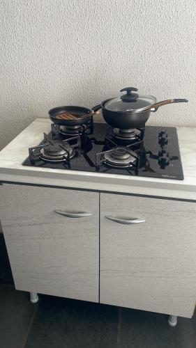 a stove top with two pans on top of it at Apartamentos na região Central Cobertura e 2 quartos in Ponta Grossa