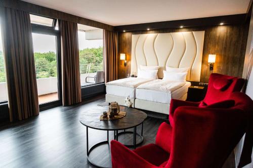 ein Hotelzimmer mit einem Bett, 2 Stühlen und einem Tisch in der Unterkunft PLAZA Premium Timmendorfer Strand in Timmendorfer Strand