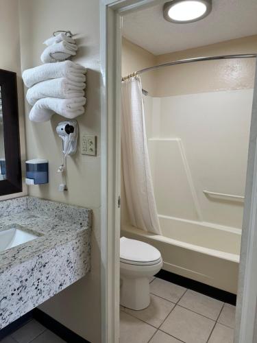 a bathroom with a toilet and a shower and towels at Ambassador Inn in Perryton