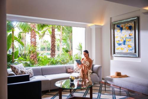 a woman sitting on a couch in a living room with a laptop at Pullman Mazagan Royal Golf & Spa in El Jadida