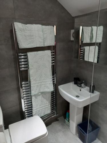 a bathroom with a sink and a toilet and towels at Flat 4, 43 Part Street in Southport