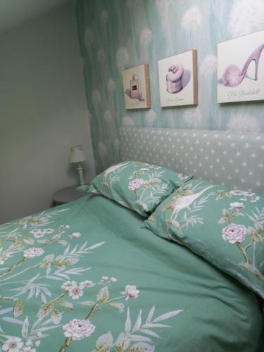 a bed with a green comforter with flowers on it at Flat 4, 43 Part Street in Southport