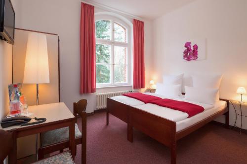 a bedroom with a bed and a desk and a window at Hotel Morgenland in Berlin