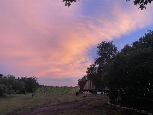 a sunset over a field with a barn and trees at 12 Fires Luxury Glamping #2 in Johnson City