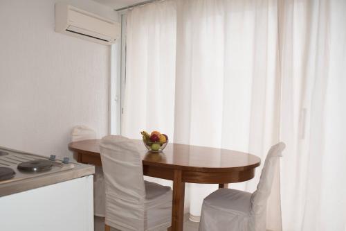 una mesa de cocina con sillas y un bol de fruta. en Apartments Kiki, en Dubrovnik