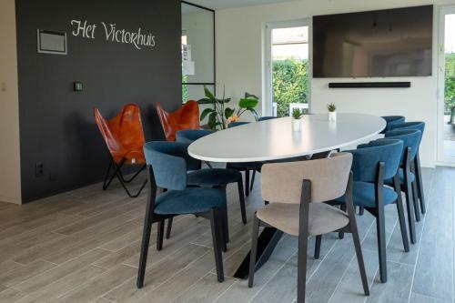 a dining room with a white table and blue chairs at Logies Ternier in Nieuwpoort