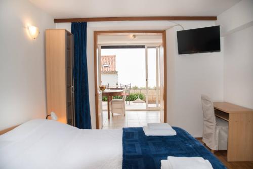 a bedroom with a bed and a television and a balcony at Apartments Kiki in Dubrovnik