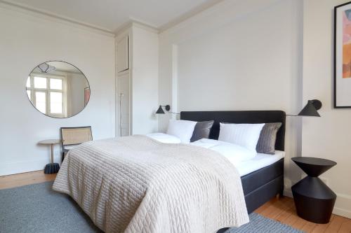 a bedroom with a large bed and a mirror at Famous Lakes Apt - City Central in Copenhagen