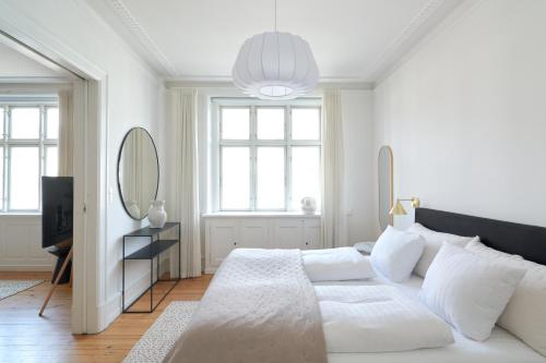 a white bedroom with a large bed and a mirror at Famous Lakes Apt - City Central in Copenhagen