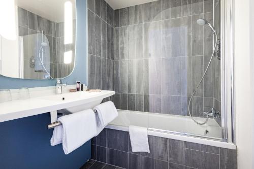 a bathroom with a tub and a sink and a shower at ibis Saint Malo Plage in Saint Malo
