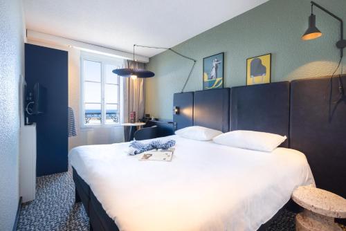 a hotel room with a large bed with a book on it at ibis Saint Malo Plage in Saint Malo