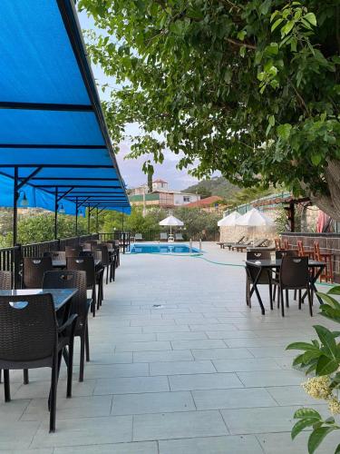 a patio with tables and chairs and a pool at Hotel Sema in Patara