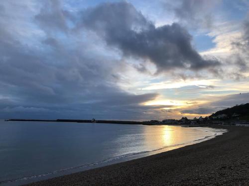 a beach with a cloudy sky and the water at Sea Cliff View Designer Home in Lyme Regis