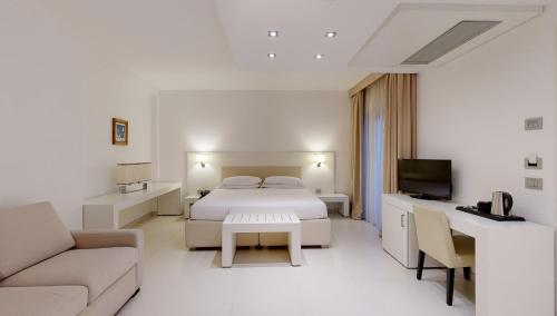 een witte slaapkamer met een bed en een bank bij Hotel Monte Sarago in Ostuni