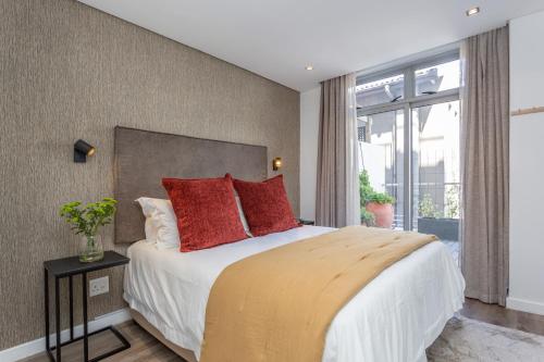 ein Schlafzimmer mit einem großen Bett mit roten Kissen in der Unterkunft Edgy On Bree in Kapstadt