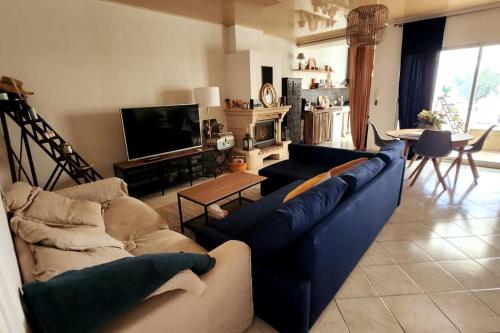 un salon avec des canapés bleus et une télévision dans l'établissement Jolie maison avec terrasse proche centre et gare, à Rochefort