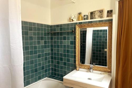 La salle de bains est pourvue d'un lavabo, d'un miroir et d'une baignoire. dans l'établissement Jolie maison avec terrasse proche centre et gare, à Rochefort