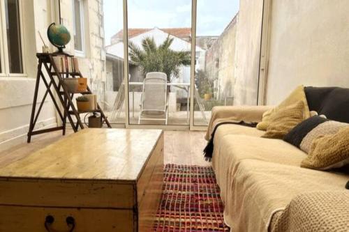 - un salon avec un canapé et une grande fenêtre dans l'établissement Jolie maison avec terrasse proche centre et gare, à Rochefort