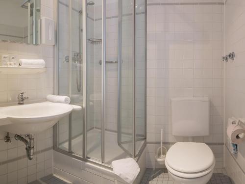 a bathroom with a shower and a toilet and a sink at Hotel Morgenland in Berlin