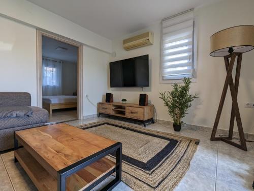 a living room with a couch and a tv at Ethos Apartment in Nea Peramos
