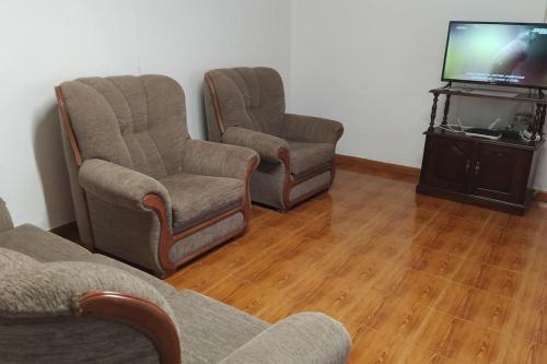 a living room with two chairs and a tv at Casa dos Fenais in Praia da Graciosa