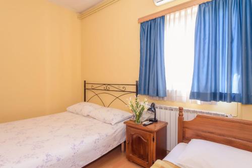 a bedroom with a bed and a window with blue curtains at Djudja I Mate in Vid