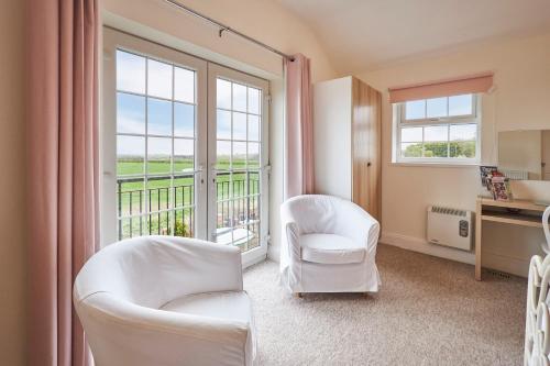 a living room with white chairs and a large window at Host & Stay - The Paddock in Bedlington