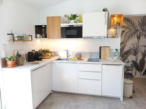 uma cozinha branca com armários brancos em Le Patio 4*. SPA, jardin, piscine en provence, proche Grignan em Saint-Paul-Trois-Châteaux