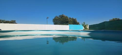 エル・カスティージョ・デ・ラス・グアルダスにあるVilla Saudade, casa entre encinasの壁の隣の青い水のプール