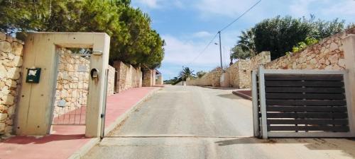 an empty street with a gate and stone walls at Kiki's Seaview Villa in Gerani