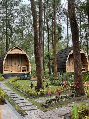 two huts in a forest with flowers and trees at Bamboo Austin Mountbatur in Baturaja
