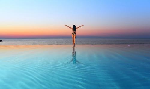 a woman standing on the beach with her arms outstretched at Acapulco Resort Hotel in Kérynia