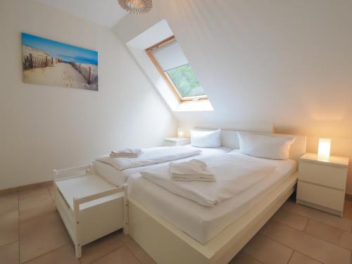 a white bedroom with two beds and a window at Haus Auguste - App. 16 in Bansin