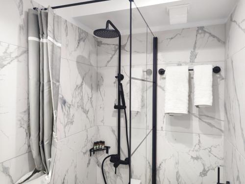 y baño con ducha y paredes de mármol blanco. en Palmeira Studio, en Preveza