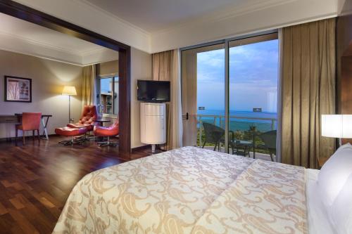 a hotel room with a bed and a view of the ocean at Acapulco Resort Hotel in Kérynia