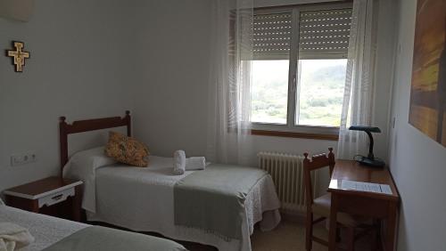 a small bedroom with two beds and a window at Hospedería Santa María do Mar in Sanxenxo