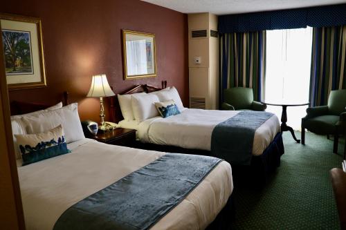 um quarto de hotel com duas camas e uma cadeira em Fort Magruder Historic Williamsburg, Trademark by Wyndham em Williamsburg