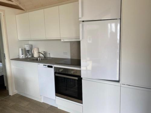 uma cozinha com armários brancos e um aparelho preto em Rosenvold Strand Camping em Stouby