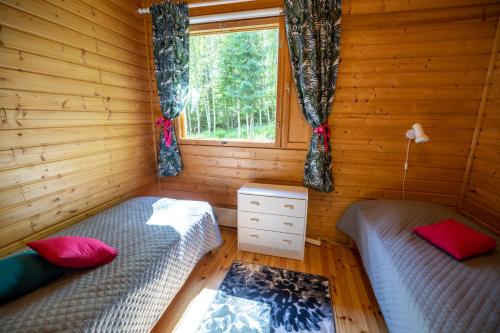 2 camas en una cabaña de madera con ventana en Villa Jukanranta, Sorjosen lomamökit, en Sulkava