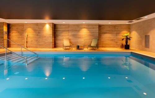 a swimming pool with two chairs in a building at DOMITYS L'HOROLOGIA in Cluses