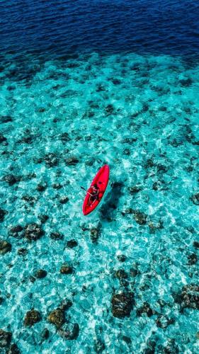 a red surfboard sitting in the blue water at Nihaali Maldives in Kudarikilu