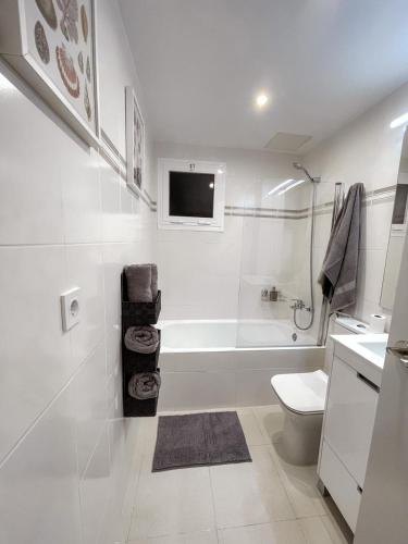 a white bathroom with a tub and a toilet at Royal in Salou