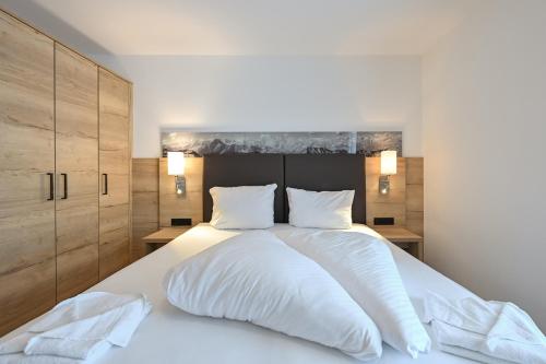 a bedroom with a large white bed with wooden cabinets at SonnenChalet Appartement SC 03 in Pfronten