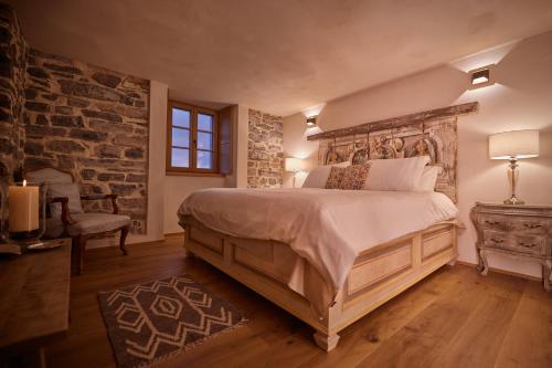 a bedroom with a large bed and a brick wall at "La Casa dei Gelsi" - Panorama Lodge MONTE GENEROSO in Scudellate
