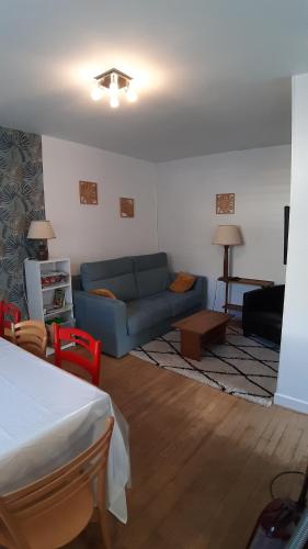 salon z niebieską kanapą i stołem w obiekcie Maison 6-9 pers pour vacances et cure thermale w mieście Mont-Dore