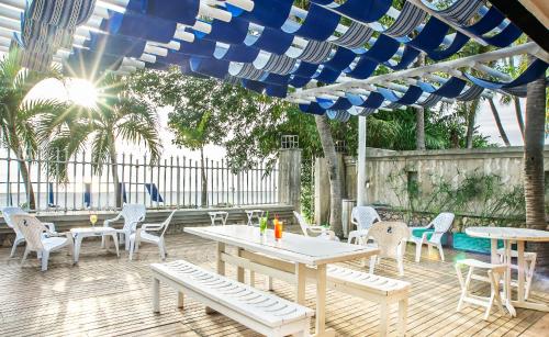 a patio with tables and chairs under a blue umbrella at Hotel Santorini Express y Cabañas in Santa Marta