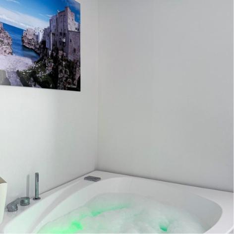 La salle de bains est pourvue d'une baignoire et d'une photo murale. dans l'établissement SUITE CALA PAURA, à Polignano a Mare