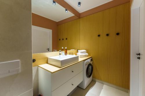 ein Badezimmer mit einem Waschbecken und einer Waschmaschine in der Unterkunft Apartament SEASHELL SurfingBird Dźwirzyno in Dźwirzyno