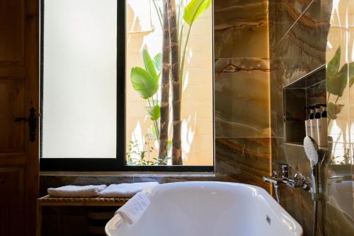 a bathroom with a tub and a window with a plant at Razzett Ziffa in Victoria